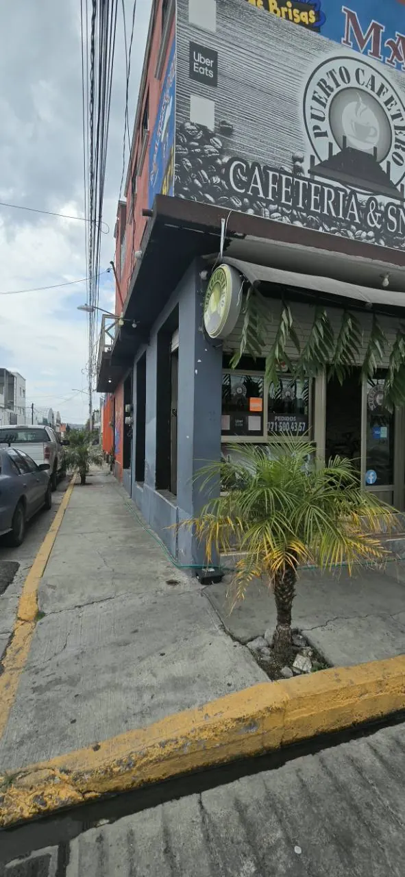 Entrada lateral de Puerto Cafetero con plantas y letrero